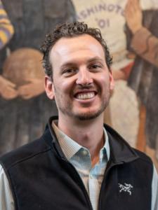Dr Peckham, a young white man with curly brown hair and a beard