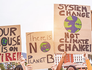 Protest with signs saying System change note climate change, There is no planet B, and Our house is on fire