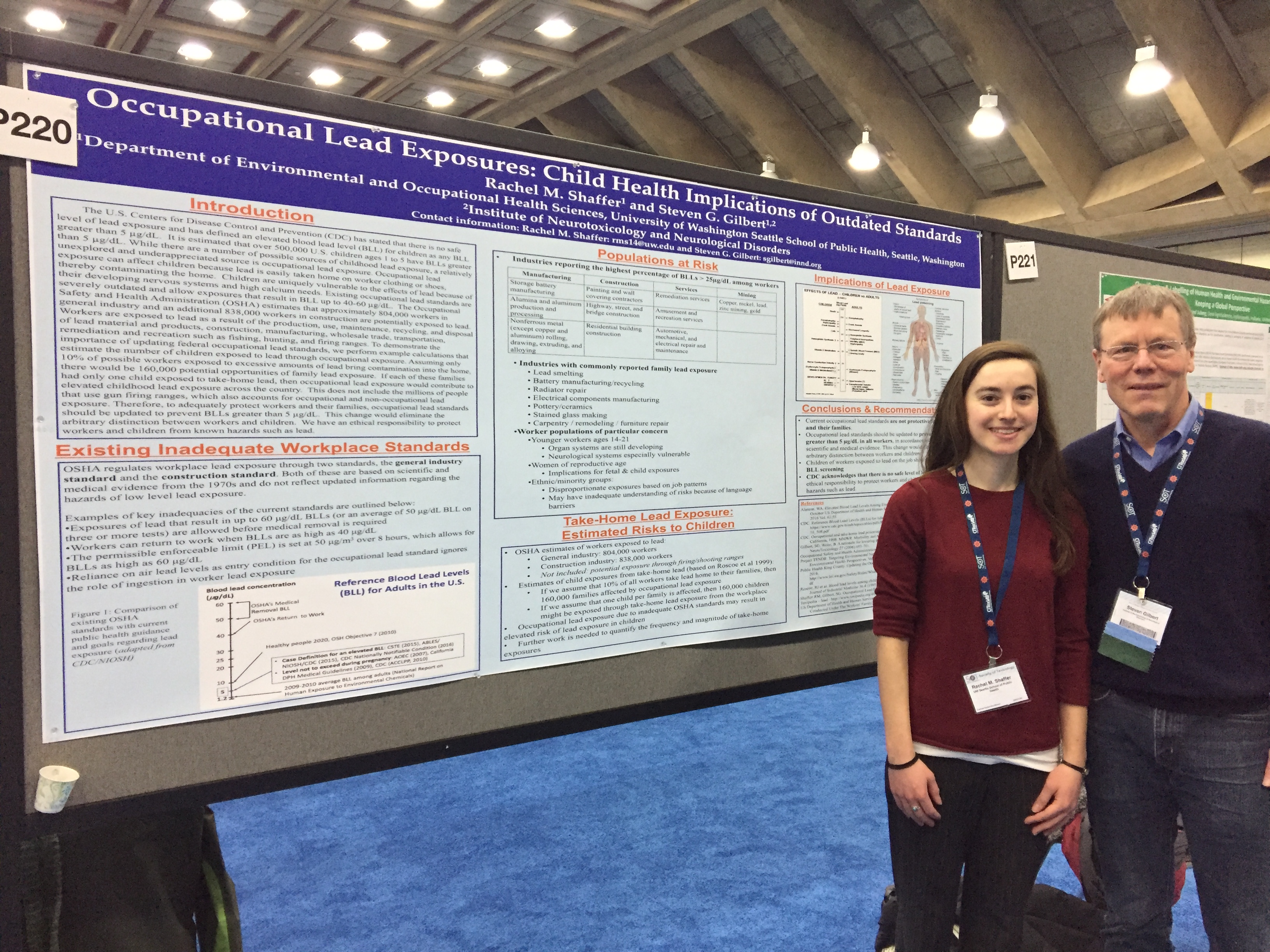 Rachel Shaffer and Steven Gilbert stand in front of a research poster reading "Occupational Lead Exposures: Child Health Implications of Outdated Standards."
