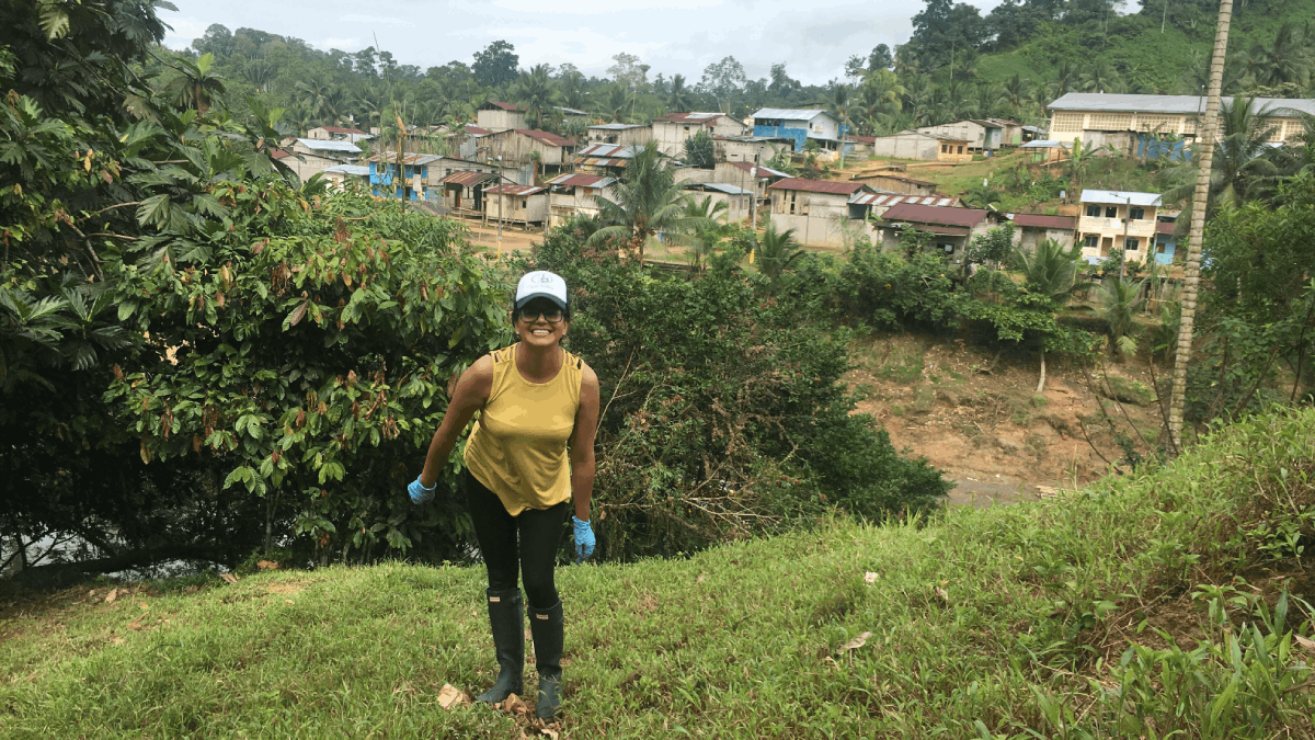Alban smiles on a hill slope with vegetation and a small village of houses in the background.