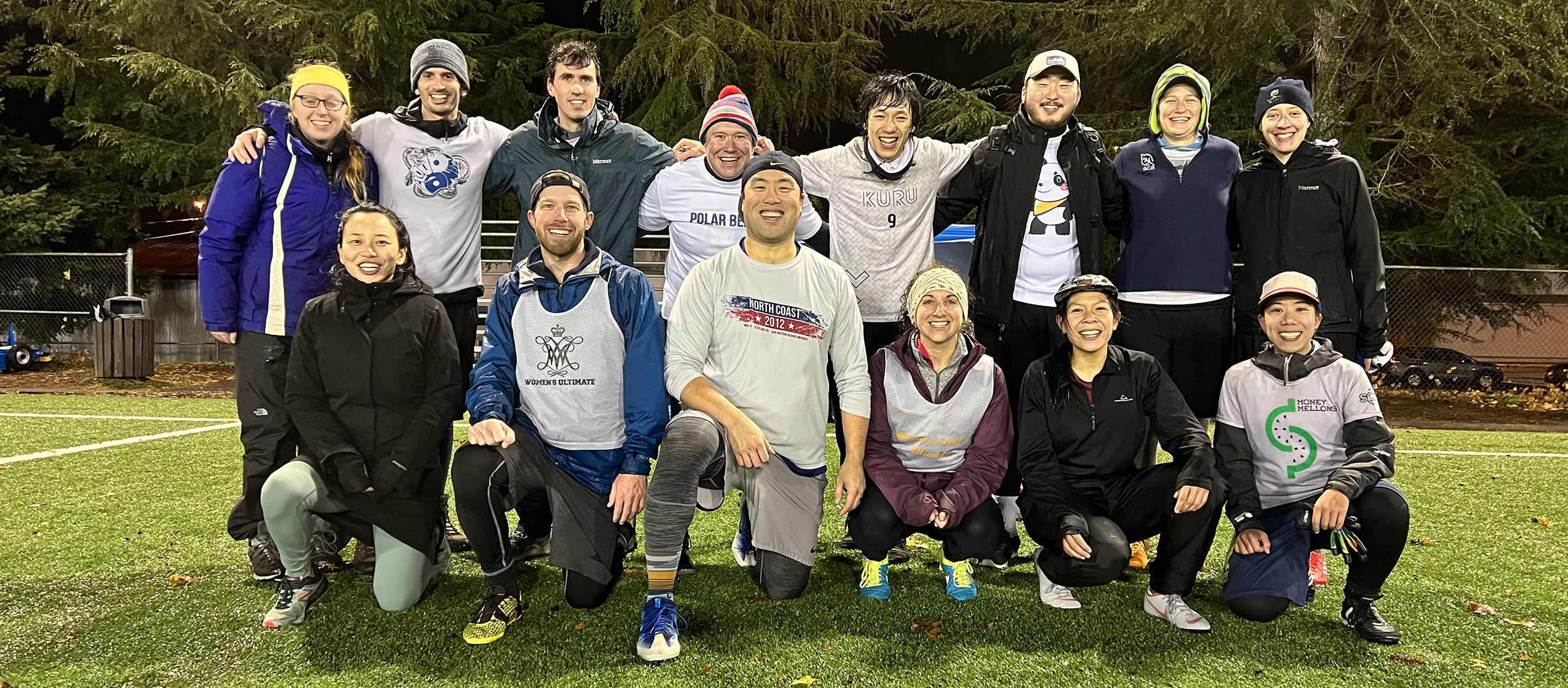 A team photo of Matsushita's ultimate frisbee team showing 14 people in two rows on a field. Matsushita is kneeling in the front row at right.