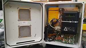 The inside of an air monitor. White metal box with hinged opening that displays the wires inside.