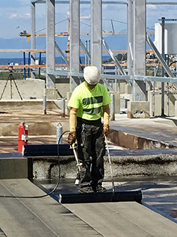 Construction worker in a hardhat works on a site in the bright sun.