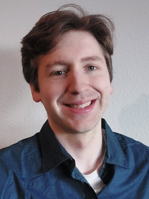 Man with short brown hair wearing dark teal shirt