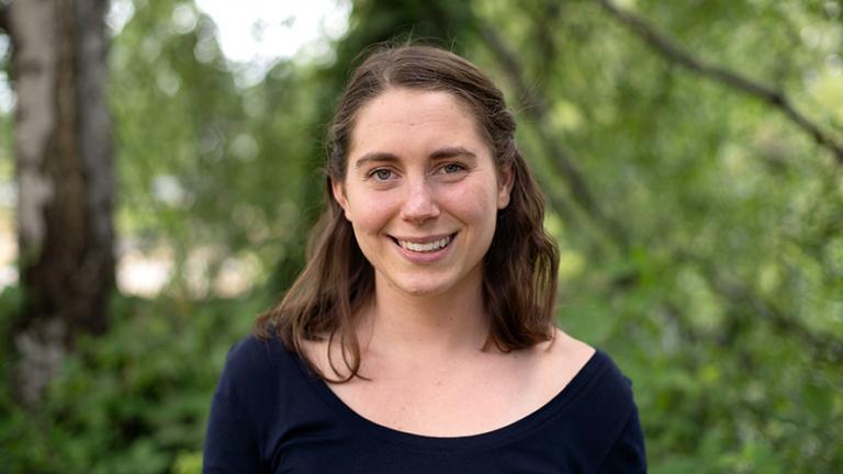 Headshot of Claire Pendergrast standing in front of a blurry leafy background. Photo: Elizar Mercado